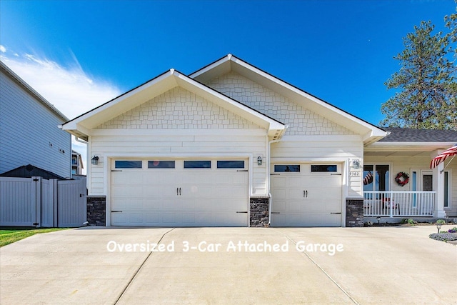 9302 W Floyd Dr, Cheney, WA 99004 - view of front facade featuring stone siding, an attached garage, concrete driveway, and covered porch