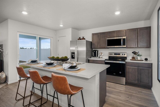 1805 E A St, Deer Park, WA 99006 - kitchen with stainless steel appliances, dark brown cabinets, a breakfast bar, light wood finished floors, and light countertops