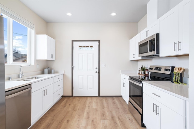 10718 E Augusta Rd, Spokane, WA 99207 - kitchen featuring appliances with stainless steel finishes, light wood finished floors, light countertops, white cabinetry, and recessed lighting