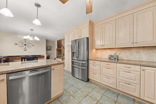 2913 E 61st Ct, Spokane, WA 99223 - kitchen featuring appliances with stainless steel finishes, cream cabinetry, backsplash, a chandelier, and pendant lighting