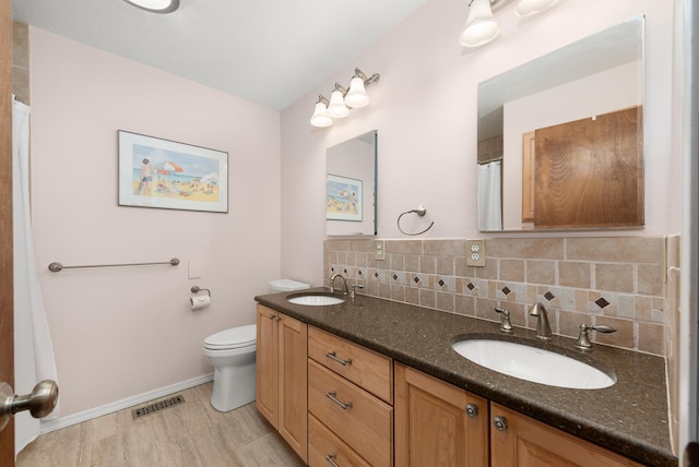2913 E 61st Ct, Spokane, WA 99223 - full bathroom with double vanity, tasteful backsplash, a shower with shower curtain, and wood finished floors
