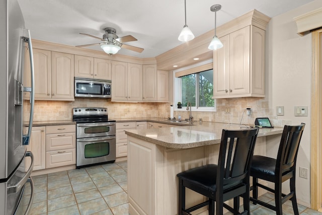 2913 E 61st Ct, Spokane, WA 99223 - kitchen with appliances with stainless steel finishes, a peninsula, a ceiling fan, light stone counters, and backsplash