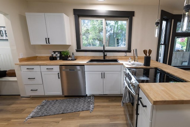 2514 4th Ave, Spokane, WA 99202 - kitchen with butcher block countertops, appliances with stainless steel finishes, light wood-type flooring, white cabinets, and a peninsula