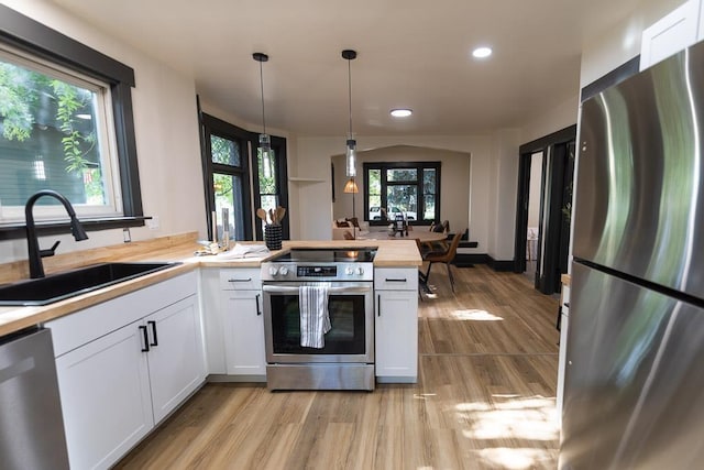 2514 4th Ave, Spokane, WA 99202 - kitchen featuring appliances with stainless steel finishes, a peninsula, recessed lighting, light wood-type flooring, and white cabinetry