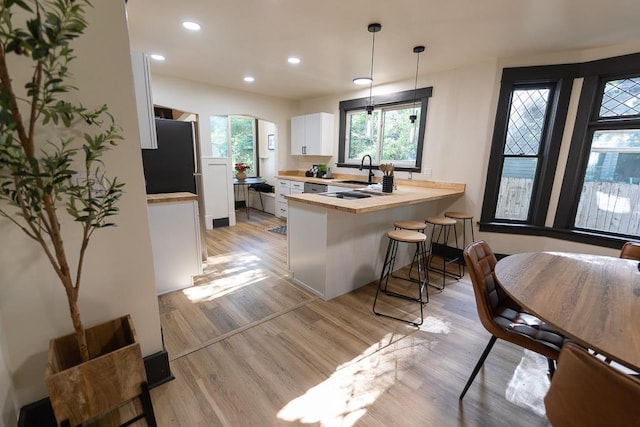 2514 4th Ave, Spokane, WA 99202 - kitchen with a peninsula, white cabinetry, light wood-type flooring, light countertops, and recessed lighting