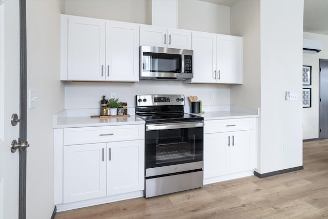 2519 N Columbus Rd, Spokane, WA 99207 - kitchen with appliances with stainless steel finishes, a wall unit AC, light wood finished floors, white cabinetry, and light countertops
