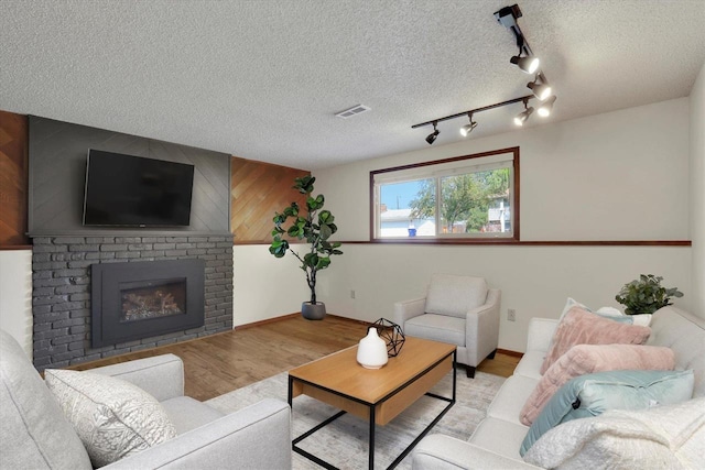 14417 N Dakota Rd, Spokane, WA 99208 - living area with wood finished floors, a fireplace, rail lighting, and a textured ceiling
