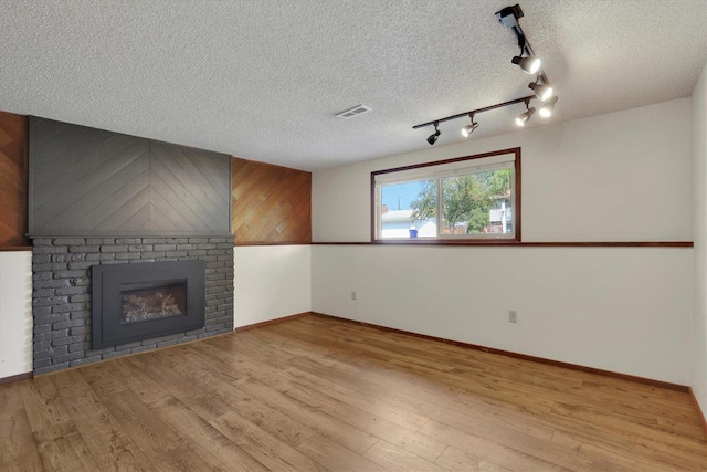14417 N Dakota Rd, Spokane, WA 99208 - unfurnished living room with wood finished floors, track lighting, a brick fireplace, and a textured ceiling