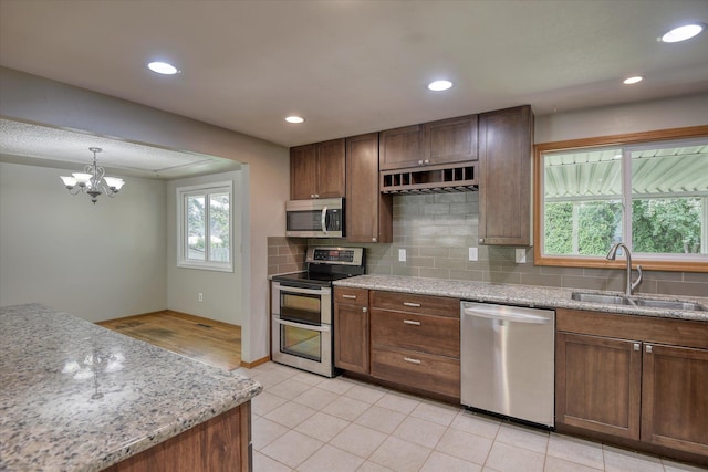 9405 N Normandie Ln, Spokane, WA 99218 - kitchen with appliances with stainless steel finishes, decorative backsplash, a chandelier, recessed lighting, and light stone counters