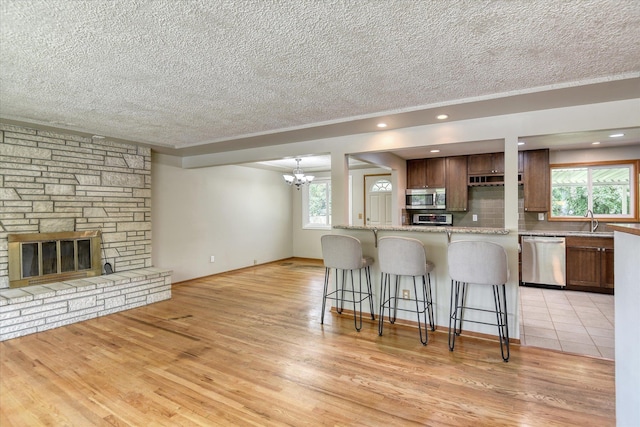 9405 N Normandie Ln, Spokane, WA 99218 - kitchen featuring appliances with stainless steel finishes, a textured ceiling, a breakfast bar area, plenty of natural light, and a chandelier