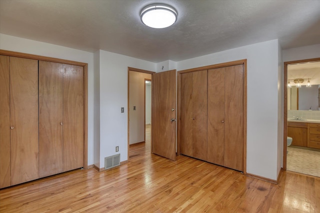 9405 N Normandie Ln, Spokane, WA 99218 - unfurnished bedroom with two closets, light wood finished floors, and connected bathroom