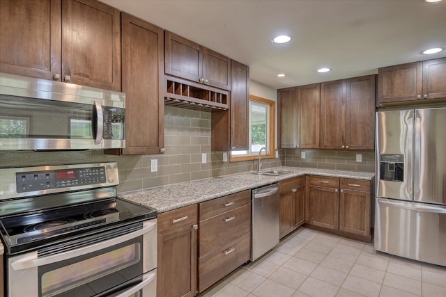 9405 N Normandie Ln, Spokane, WA 99218 - kitchen with appliances with stainless steel finishes, light tile patterned floors, decorative backsplash, light stone countertops, and recessed lighting