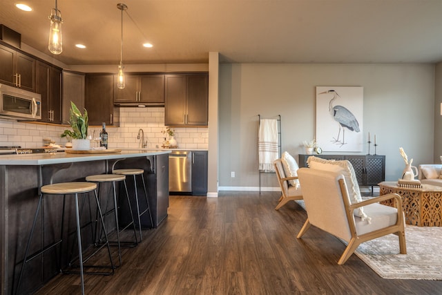 2303 W Bridge Ave, Spokane, WA 99201 - kitchen featuring appliances with stainless steel finishes, dark wood-style floors, dark brown cabinets, tasteful backsplash, and light countertops
