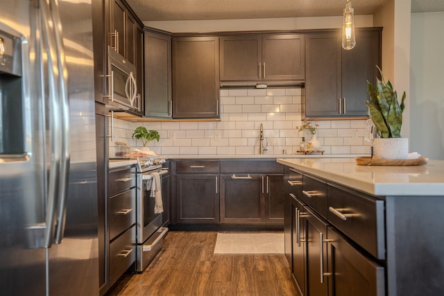 2303 W Bridge Ave, Spokane, WA 99201 - kitchen with stainless steel appliances, dark wood-style floors, dark brown cabinets, tasteful backsplash, and light countertops