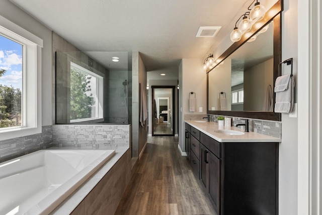 4513 S Crows Nest Ln, Spokane, WA 99206 - full bathroom featuring double vanity, a garden tub, wood finished floors, a tile shower, and backsplash