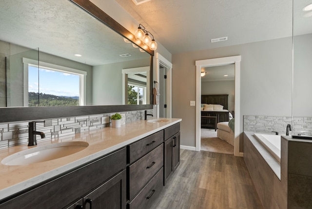4513 S Crows Nest Ln, Spokane, WA 99206 - ensuite bathroom with wood finished floors, tasteful backsplash, double vanity, a bath, and recessed lighting