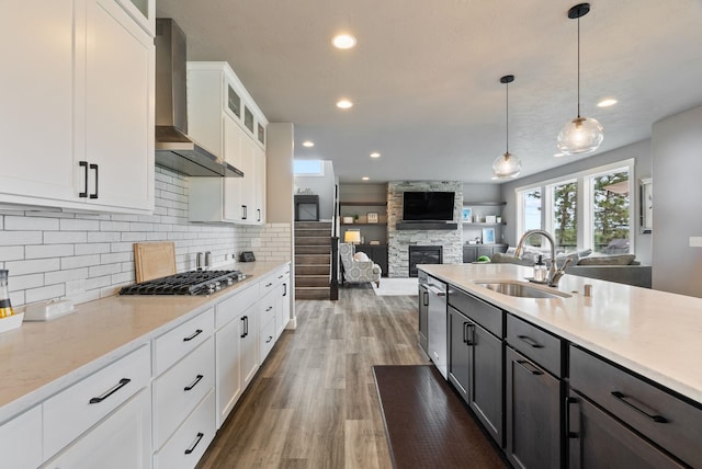 4513 S Crows Nest Ln, Spokane, WA 99206 - kitchen with wall chimney range hood, appliances with stainless steel finishes, a stone fireplace, open floor plan, and wood finished floors