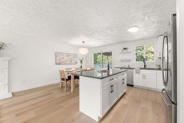 7721 N Wilding Dr, Spokane, WA 99208 - kitchen with appliances with stainless steel finishes, dark countertops, a textured ceiling, white cabinets, and light wood finished floors
