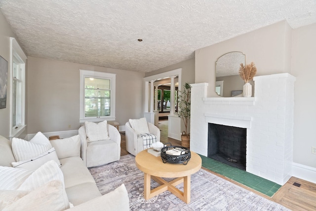 1315 N Hollis St, Spokane, WA 99201 - living room featuring a textured ceiling, a brick fireplace, and wood finished floors