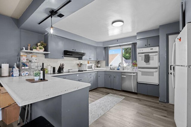 1630 E Broad Ave, Spokane, WA 99207 - kitchen with white appliances, a peninsula, gray cabinets, open shelves, and light wood-type flooring