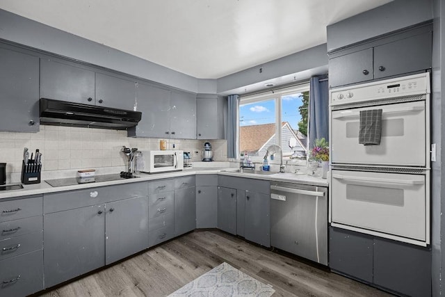 1630 E Broad Ave, Spokane, WA 99207 - kitchen with white appliances, under cabinet range hood, gray cabinetry, and tasteful backsplash