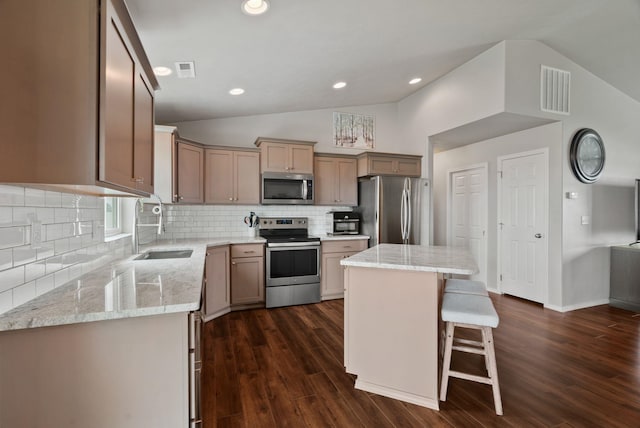 818 S Apple Pl, Spokane, WA 99224 - kitchen featuring stainless steel appliances, vaulted ceiling, a kitchen island, light stone countertops, and a breakfast bar area