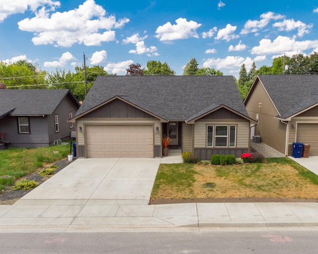 4017 E Hartson Ave, Spokane, WA 99202 - view of front of house with board and batten siding, a garage, concrete driveway, a front yard, and roof with shingles