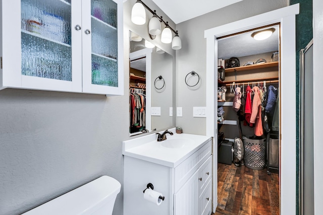 2202 E 50th Ave, Spokane, WA 99223 - bathroom featuring a walk in closet, vanity, and wood finished floors