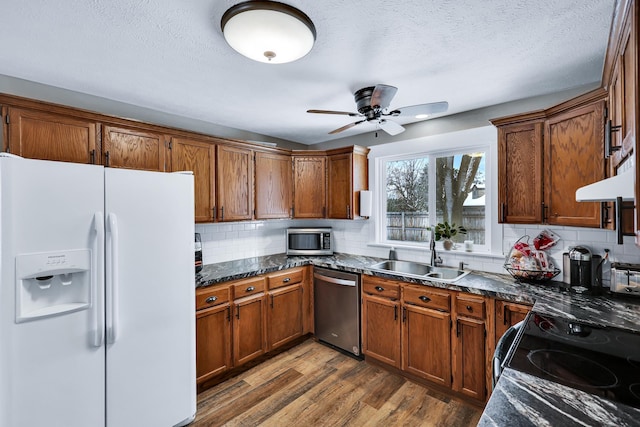 2202 E 50th Ave, Spokane, WA 99223 - kitchen featuring stainless steel appliances, brown cabinets, tasteful backsplash, wood finished floors, and a textured ceiling