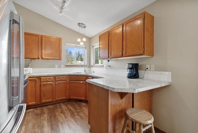 3224 E 42nd Ave, Spokane, WA 99223 - kitchen featuring stainless steel refrigerator, lofted ceiling, a peninsula, dark wood-style flooring, and brown cabinets