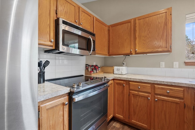 3224 E 42nd Ave, Spokane, WA 99223 - kitchen featuring appliances with stainless steel finishes, light countertops, tasteful backsplash, brown cabinetry, and dark wood-type flooring