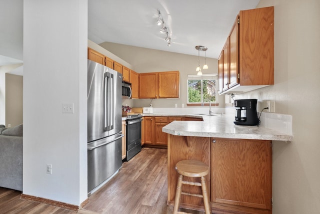 3224 E 42nd Ave, Spokane, WA 99223 - kitchen with stainless steel appliances, lofted ceiling, a peninsula, wood finished floors, and light countertops