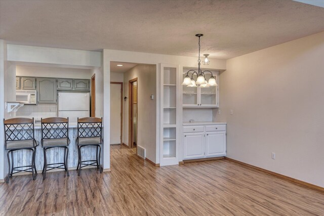 3023 S Winthrop Ln Unit 3023, Spokane, WA 99203 - kitchen featuring white appliances, wood finished floors, a chandelier, a breakfast bar area, and a textured ceiling