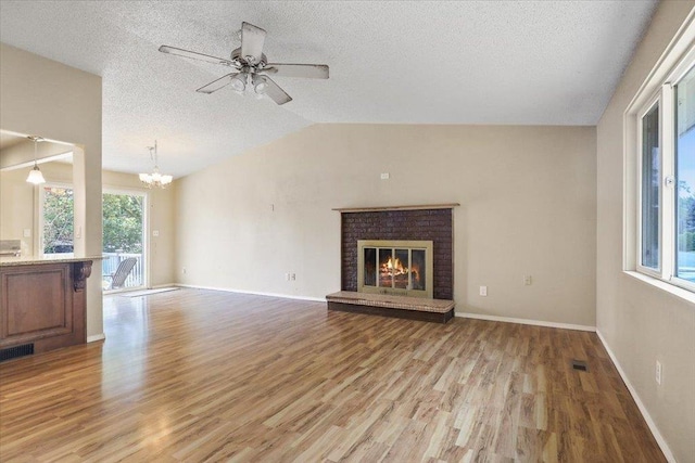 1707 S Early Dawn Dr, Spokane Valley, WA 99037 - unfurnished living room with light wood-type flooring, a chandelier, lofted ceiling, a brick fireplace, and a textured ceiling