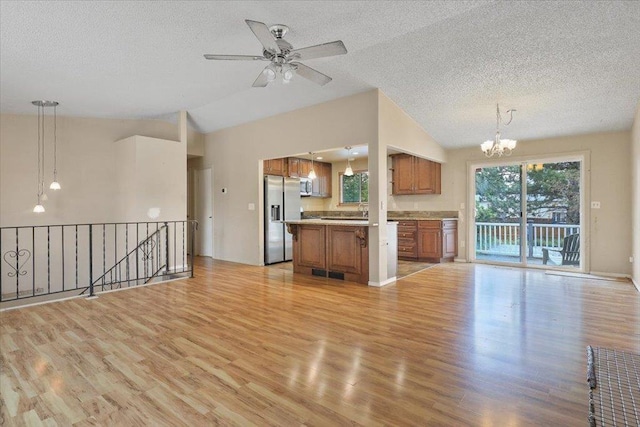 1707 S Early Dawn Dr, Spokane Valley, WA 99037 - unfurnished living room featuring a chandelier, vaulted ceiling, light wood-style floors, a textured ceiling, and a ceiling fan