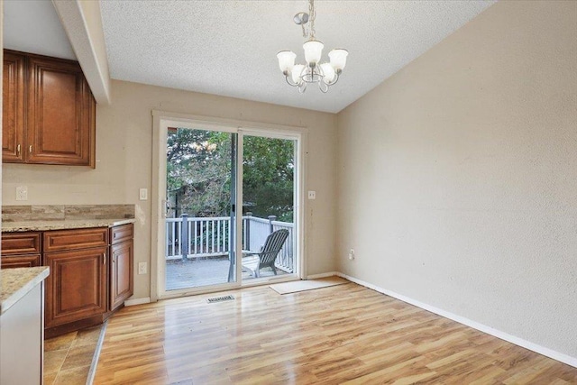 1707 S Early Dawn Dr, Spokane Valley, WA 99037 - unfurnished dining area with a chandelier, light wood-style floors, and a textured ceiling