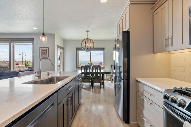 8814 E Clearview Ln, Spokane, WA 99217 - kitchen with stainless steel appliances, light wood-style floors, a chandelier, tasteful backsplash, and decorative light fixtures