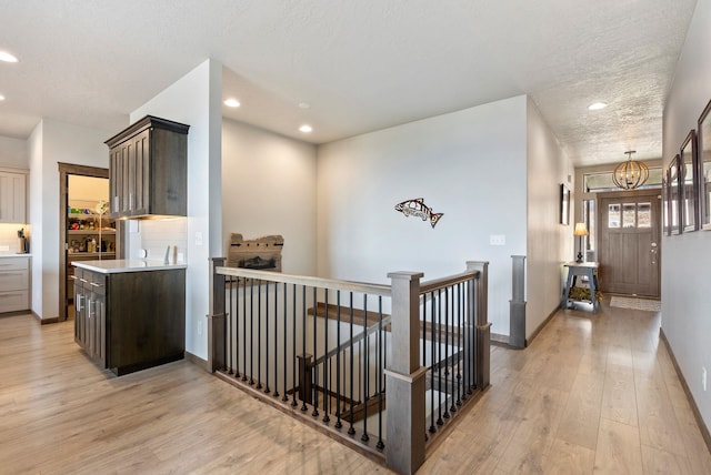 8814 E Clearview Ln, Spokane, WA 99217 - corridor with light wood-type flooring, a textured ceiling, recessed lighting, an upstairs landing, and a chandelier