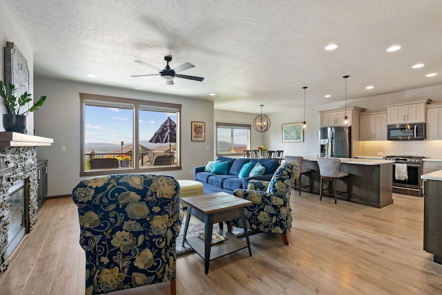 8814 E Clearview Ln, Spokane, WA 99217 - living room with recessed lighting, light wood-style flooring, a textured ceiling, a fireplace, and ceiling fan