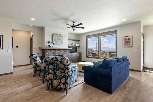 8814 E Clearview Ln, Spokane, WA 99217 - living area with a ceiling fan, light wood-type flooring, a stone fireplace, a textured ceiling, and recessed lighting