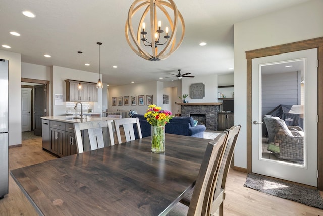 8814 E Clearview Ln, Spokane, WA 99217 - dining room with light wood finished floors, a ceiling fan, recessed lighting, a stone fireplace, and a chandelier