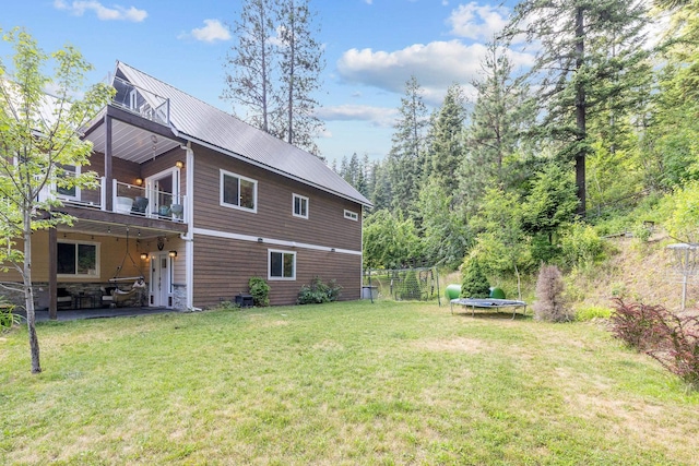 4171 S Westway Dr, Coeur D Alene, ID 83814 - view of side of property featuring a trampoline, a yard, a metal roof, and a patio