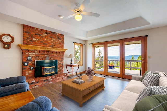 10207 N Comanche Dr, Spokane, WA 99208 - living area with wood finished floors, a ceiling fan, a fireplace, and a raised ceiling