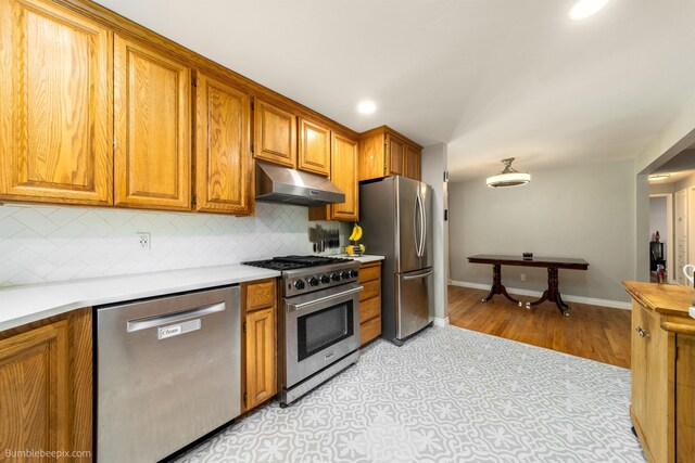 224 W Hoerner Ave, Spokane, WA 99218 - kitchen featuring appliances with stainless steel finishes, under cabinet range hood, decorative backsplash, light countertops, and brown cabinets