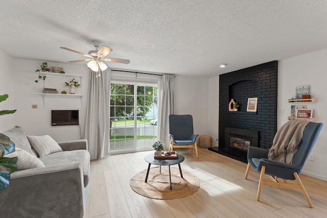 7878 N Wilding Dr # 32, Spokane, WA 99208 - living area with a brick fireplace, a textured ceiling, a ceiling fan, light wood-style flooring, and an AC wall unit