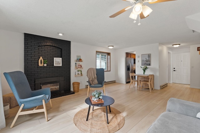 7878 N Wilding Dr # 32, Spokane, WA 99208 - living area featuring a fireplace, light wood-type flooring, a ceiling fan, a baseboard radiator, and a textured ceiling