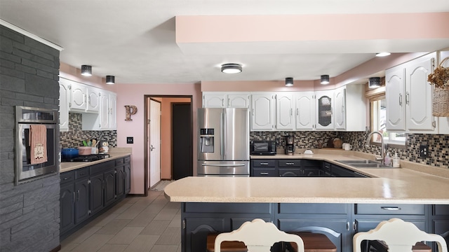 709 W Clay Ave, Chewelah, WA 99109 - kitchen featuring stainless steel appliances, a peninsula, white cabinetry, and tasteful backsplash