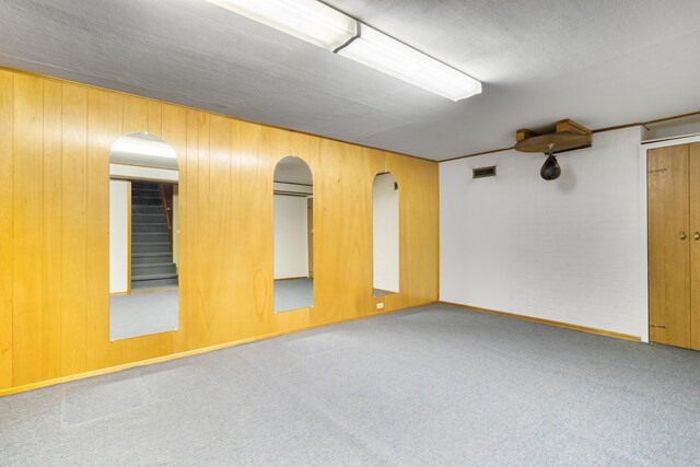 4112 S Hogan St, Spokane, WA 99203 - unfurnished room featuring carpet floors, wood walls, and stairway
