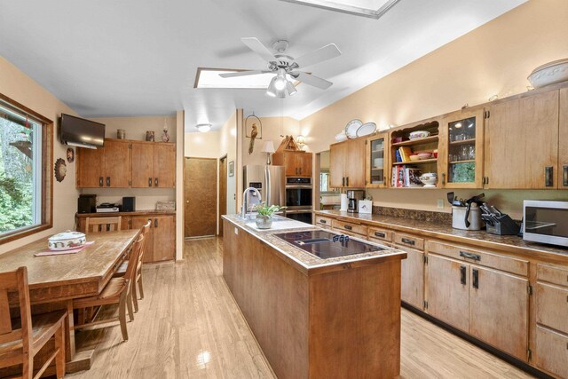 13614 N Minihdoka Trl, Spokane, WA 99208 - kitchen with appliances with stainless steel finishes, an island with sink, light wood-style floors, and a ceiling fan