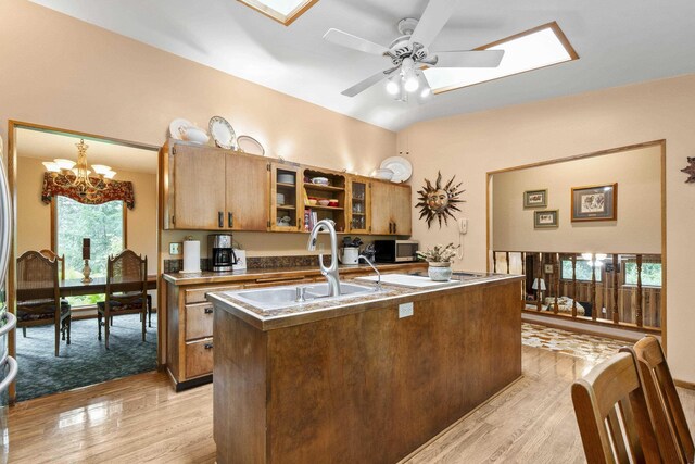 13614 N Minihdoka Trl, Spokane, WA 99208 - kitchen with light wood-style flooring, brown cabinetry, a chandelier, and an island with sink
